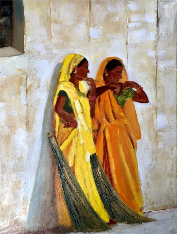 An oil painting by Grace McKee of two women in yellow and orange saris beside a pale stone wall.
